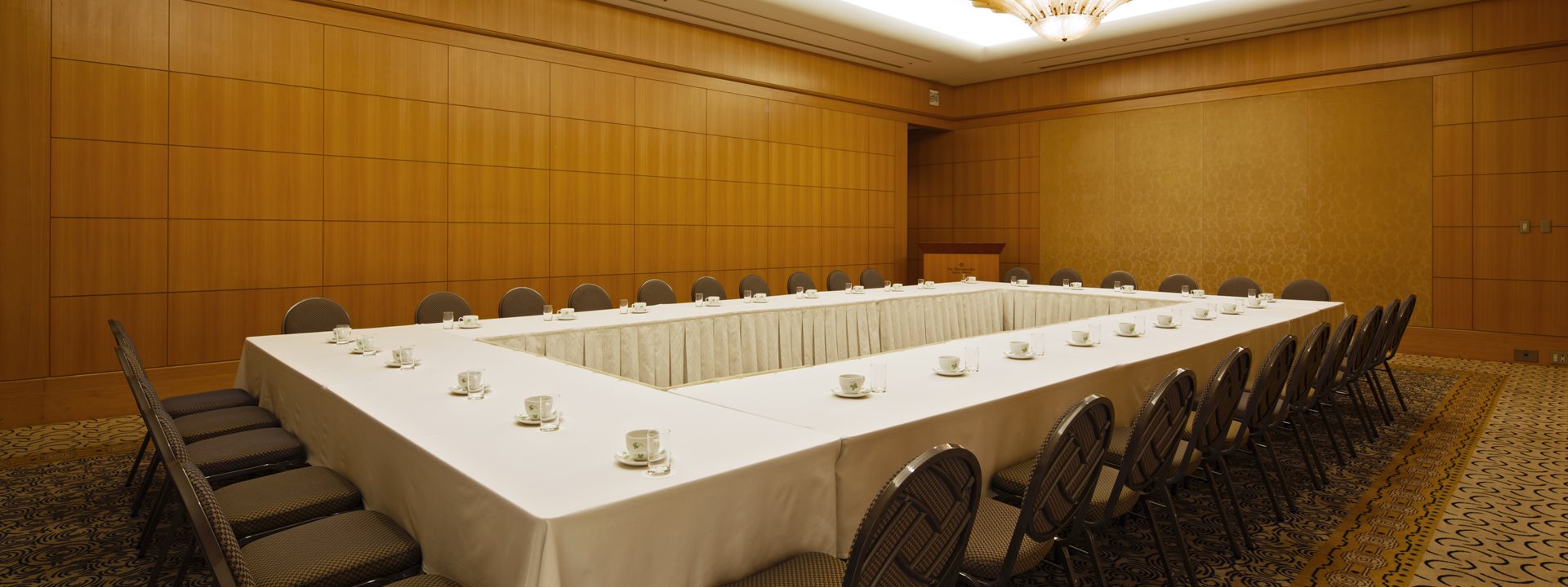 The "Admiral" banquet hall at the Yokohama Bay Hotel Tokyu. The tables and chairs are set up in a hollow square style. Photographed from an angle.