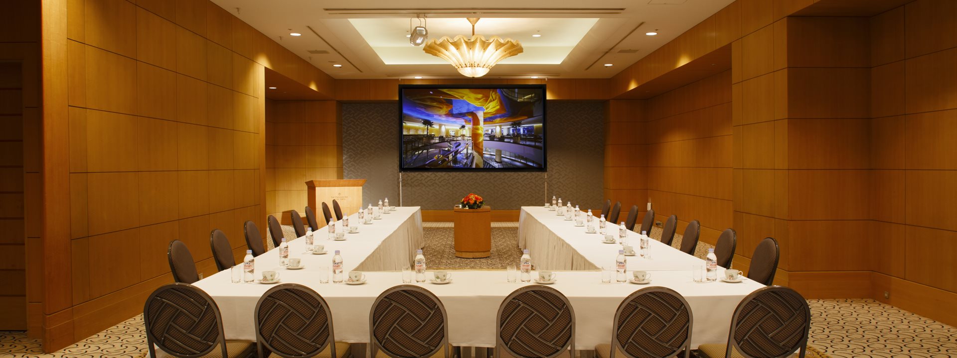 The "Prince" banquet hall at Yokohama Bay Hotel Tokyu. A monitor is installed at the front, and the tables and chairs are arranged in a U-shape. Photo taken from the rear, facing forward.