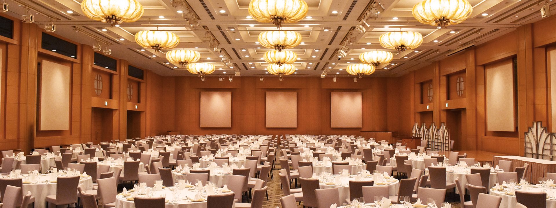 The scene in the "Queen's Grand Ballroom", the grand banquet hall of the Yokohama Bay Hotel Tokyu, features a formal dinner-style layout with numerous round tables lined up.